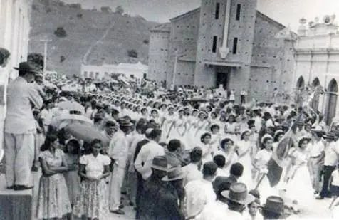 Grupo numeroso de pessoas reunidas em uma rua diante de uma igreja