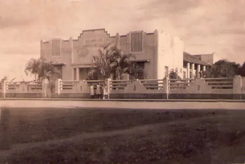 Edifício antigo visto da rua, com pessoas próximas à entrada