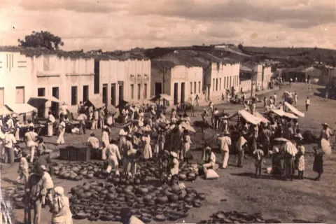 Feira antiga movimentada em uma rua, com pessoas e mercadorias