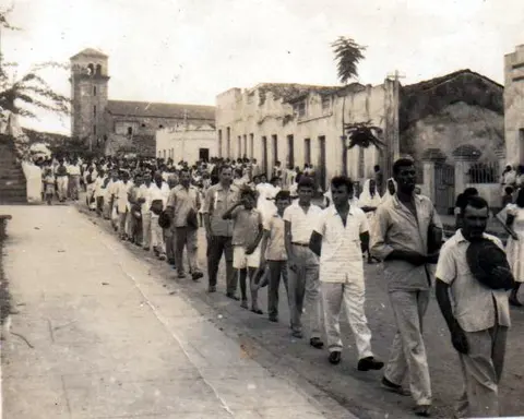 Pessoas caminhando em grupo por uma rua antiga