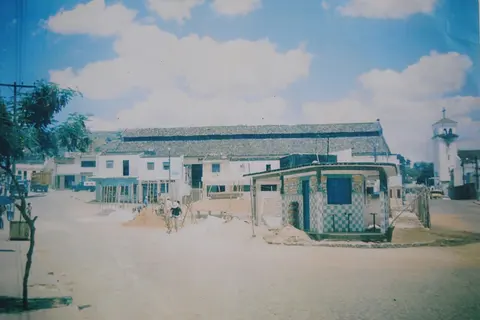 Vista de um mercado, construções e torre de igreja ao fundo