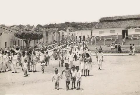 Pessoas desfilando por uma rua diante do mercado
