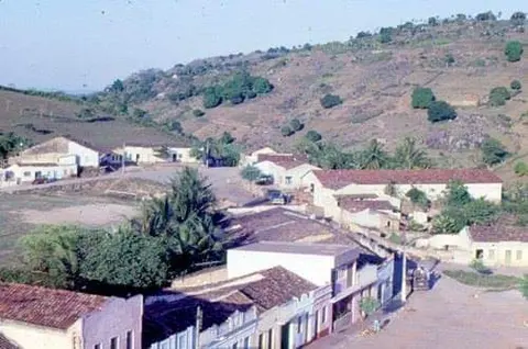 Casas diante de uma serra em fotografia colorida antiga